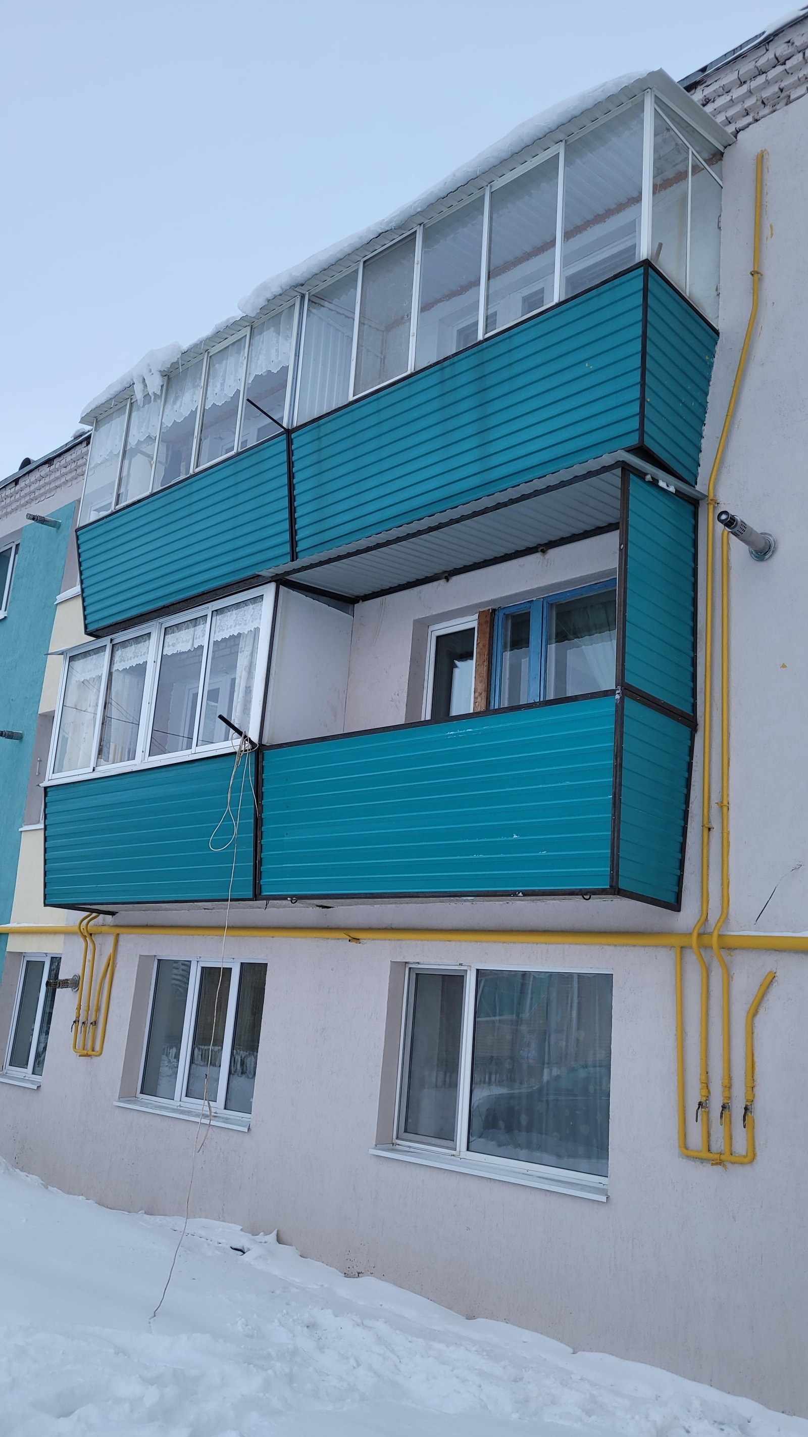 Бирюзовый балкон на фасаде многоквартирного дома.