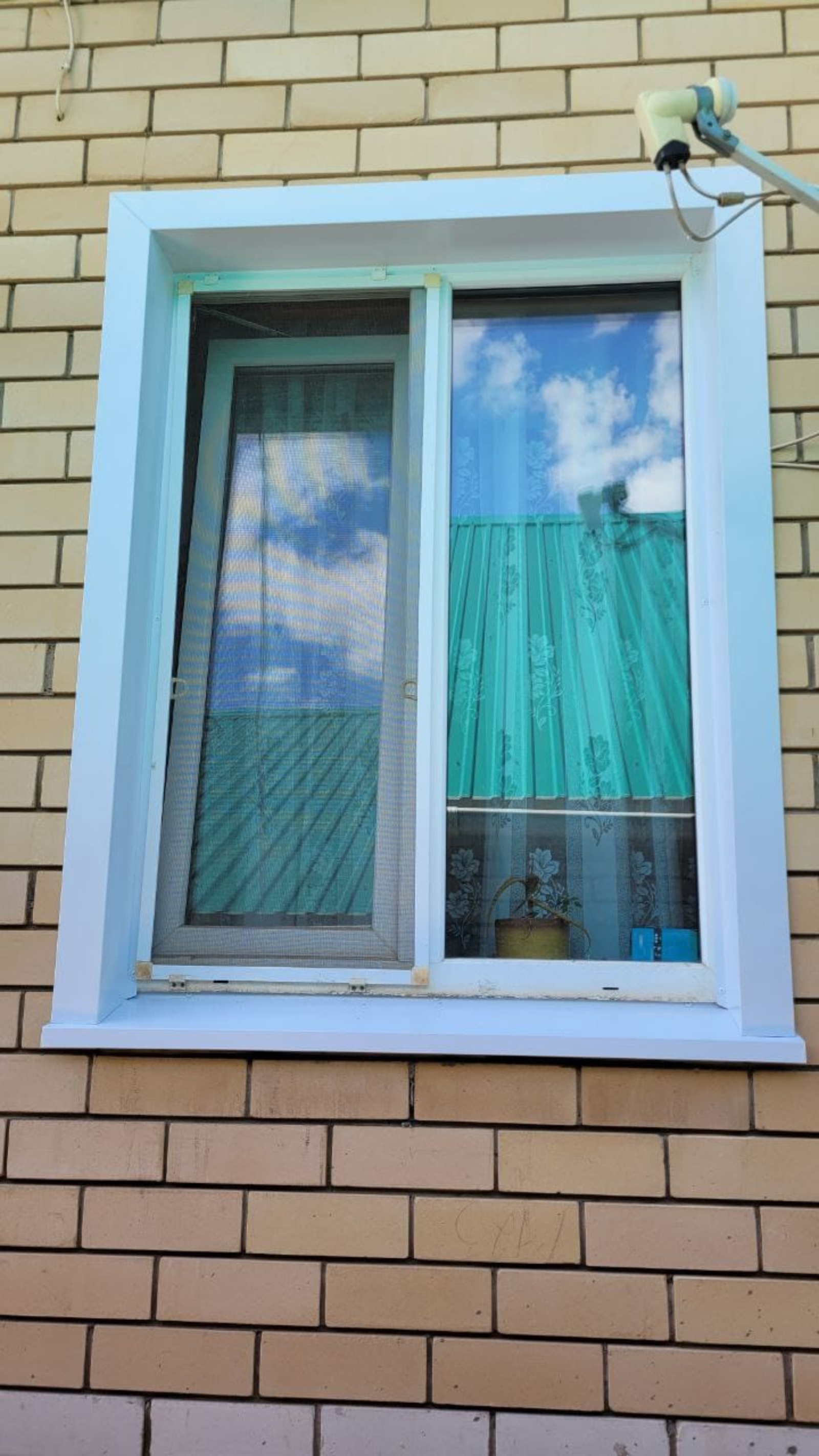 Окно с белыми наружными откосами на кирпичном фасаде.