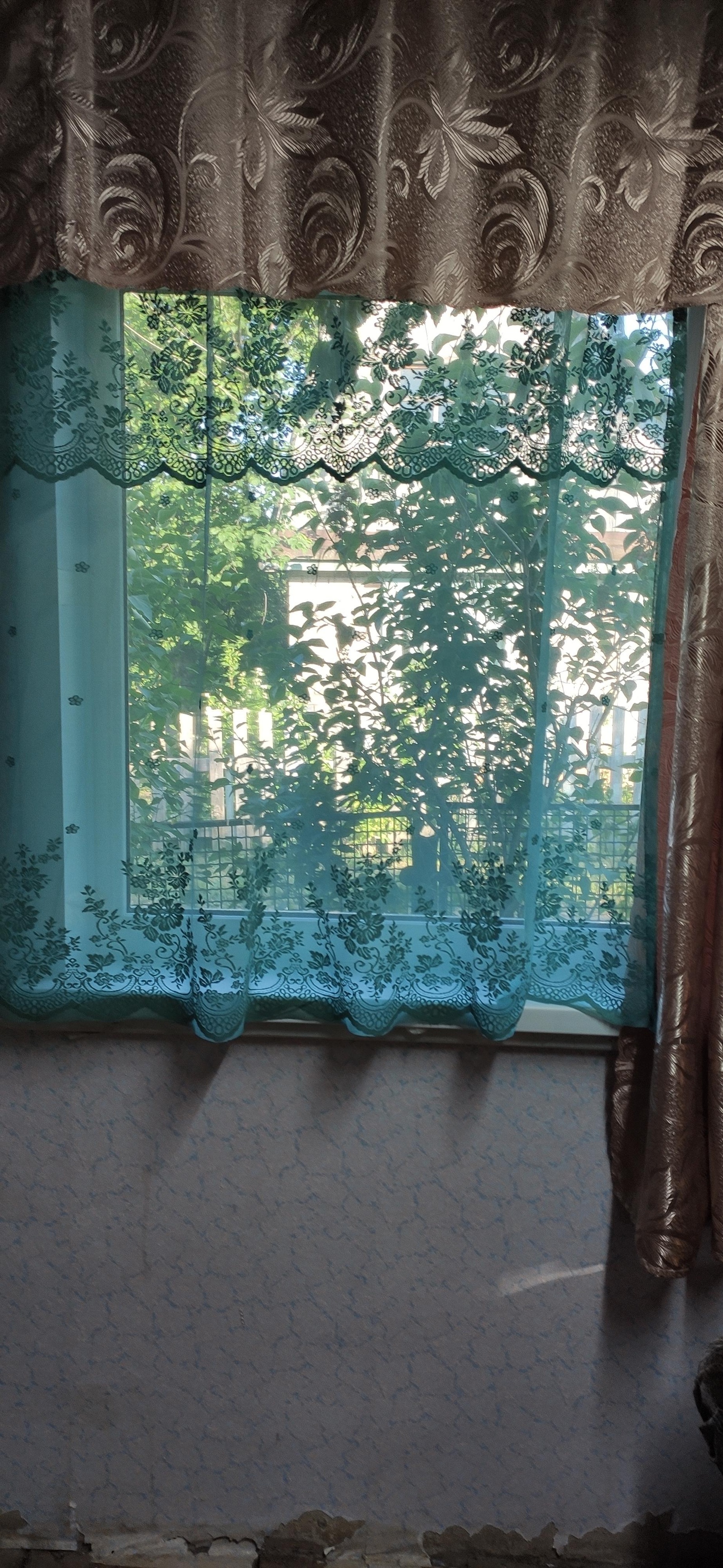Окно в комнате с узорчатой шторой.